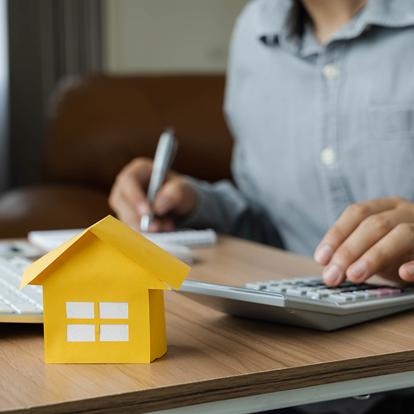Un homme assis à un bureau avec une calculatrice et une maison.