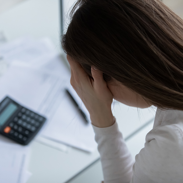 Femme assise à un bureau, la tête entre les mains