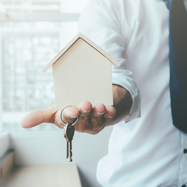 Un homme tenant un modèle de maison et des clés