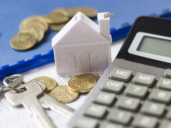 Calculatrice, maquette de maison, clés et pièces sur un bureau avec marge de crédit hypothécaire.