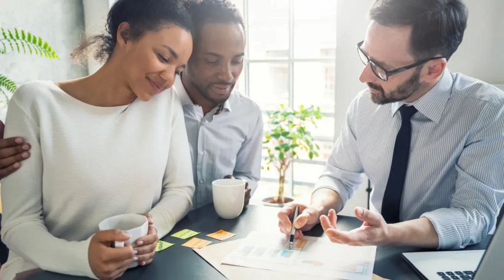Trois personnes assises à une table avec un ordinateur portable et du café.