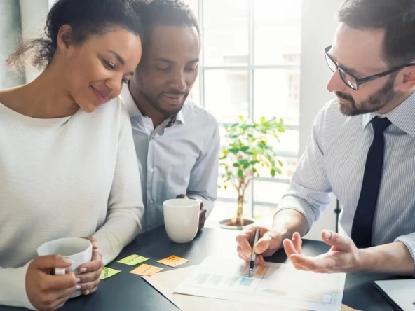 Trois personnes assises à une table avec un ordinateur portable et du café.