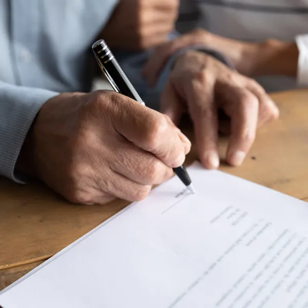 Un couple de personnes âgées signant un document pour acheter une maison sans mise de fonds et avec un mauvais crédit.